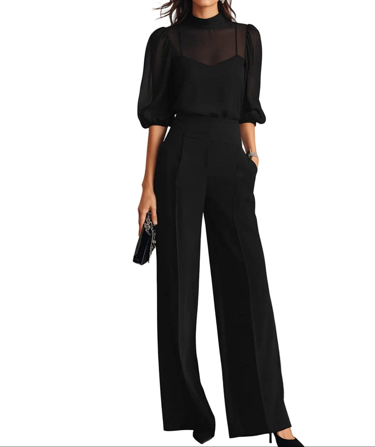 Frau vor weißem Hintergrund trägt das schwarze Set aus transparentem Oberteil mit Puffärmeln, Trägertop und weiter Hose, dazu eine Clutch. 1