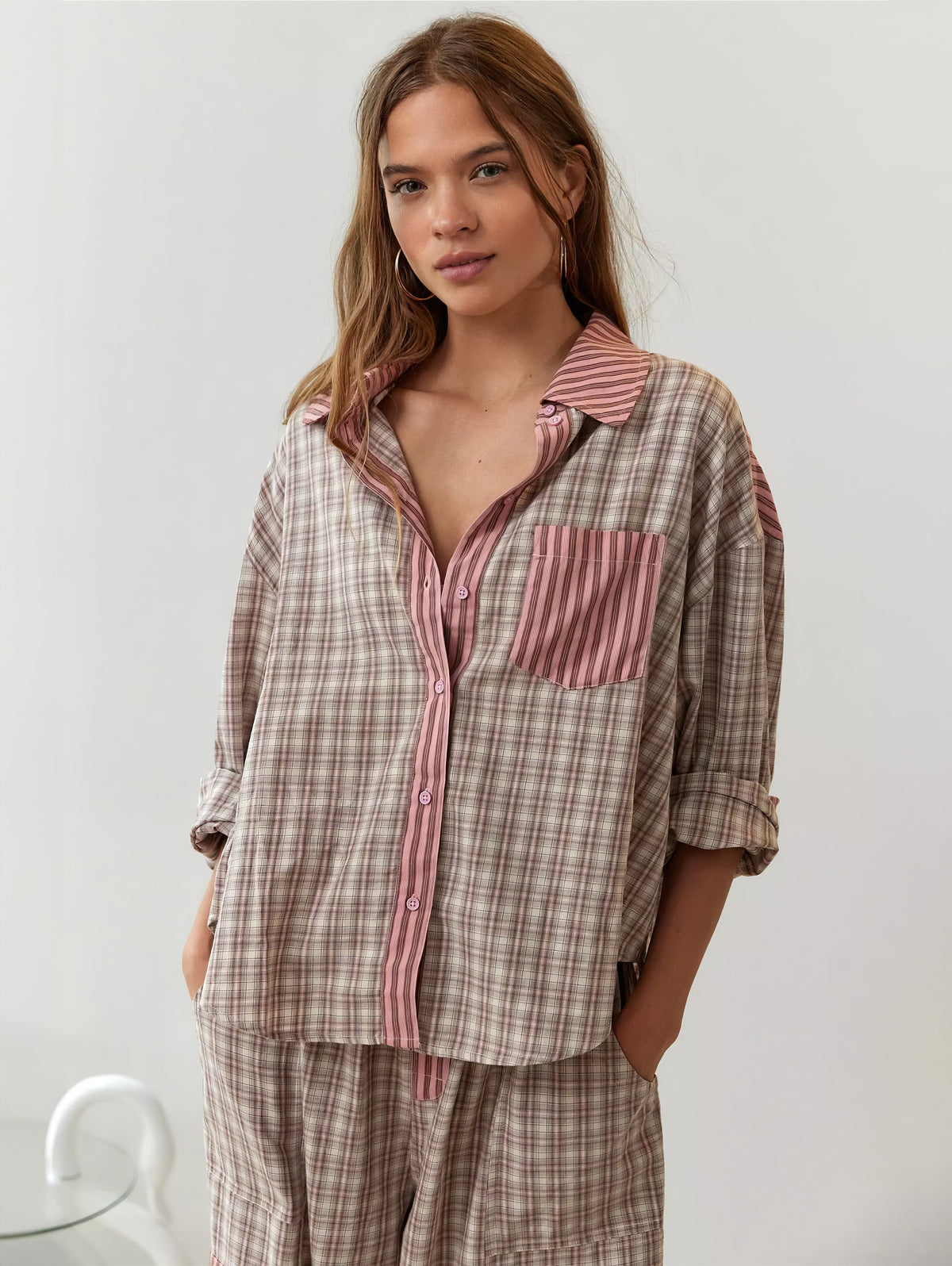 Frontale Nahaufnahme des rosa-beige karierten Pyjama-Hemds mit rosa gestreifter Knopfleiste und Brusttasche, die Ärmel hochgekrempelt. 4