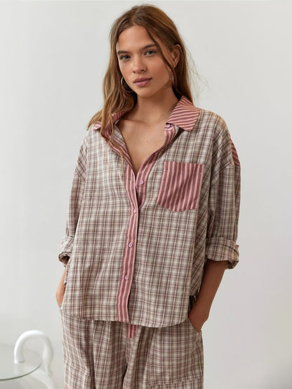 Frontale Nahaufnahme des rosa-beige karierten Pyjama-Hemds mit rosa gestreifter Knopfleiste und Brusttasche, die Ärmel hochgekrempelt. 4