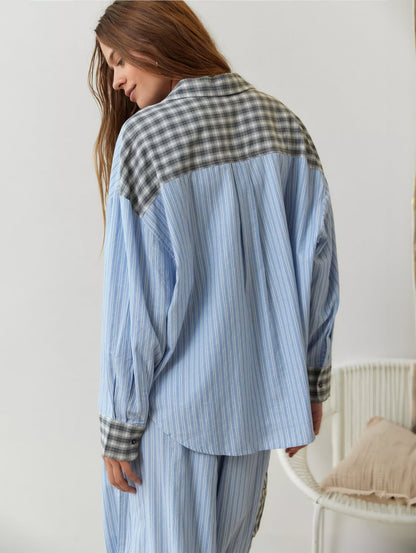 Rückansicht des blau gestreiften Pyjama-Hemds mit grau kariertem Schulterpasse und karierten Manschetten, das Model blickt nach unten. 9