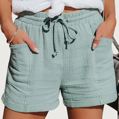 Die Shorts in Mintgrün, getragen mit weißem Knotenoberteil, Hände in den aufgesetzten Taschen, Säume nach oben umgeschlagen. 5