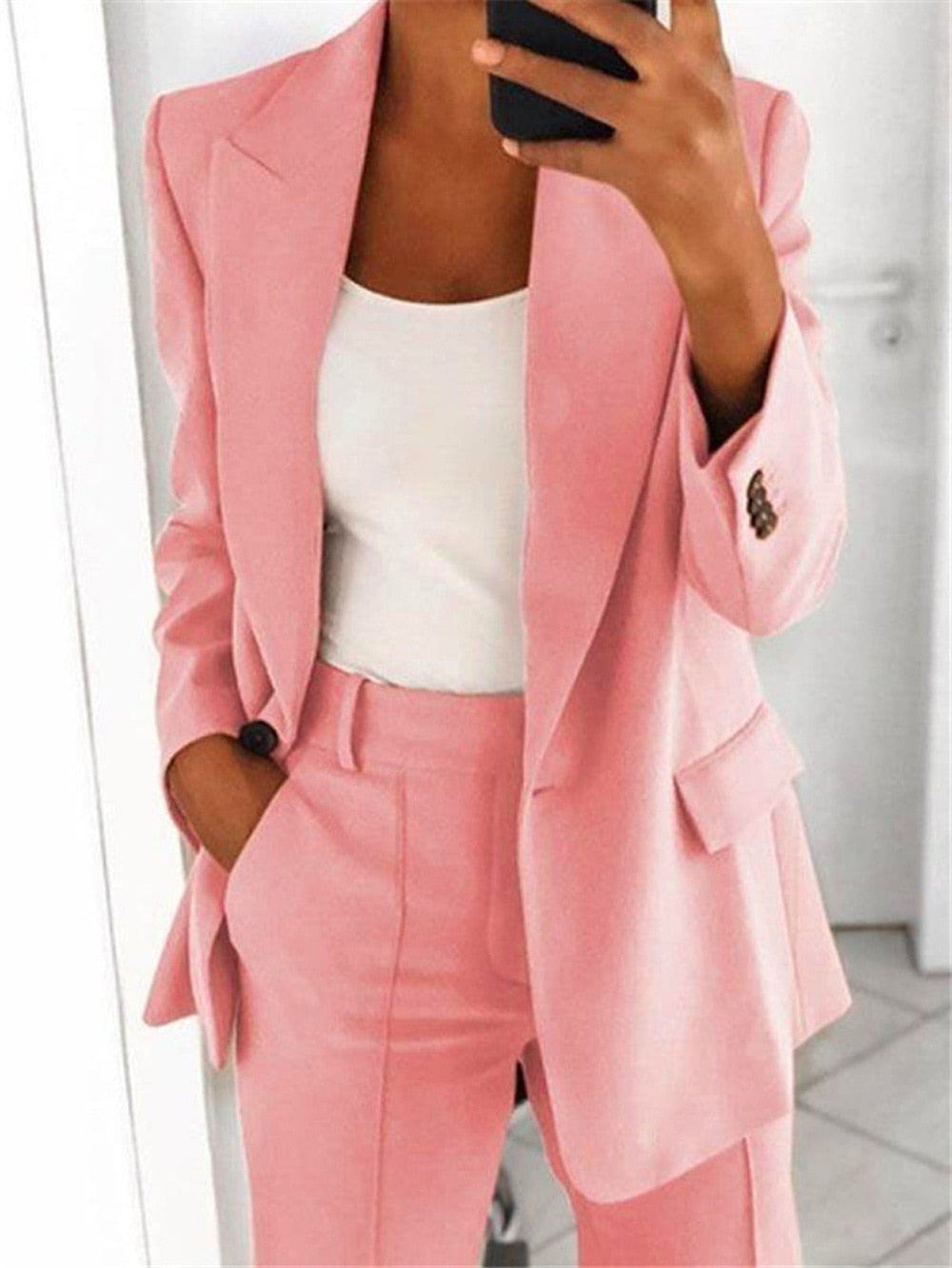 Frau im rosa Anzug mit weißem Top, Businessmode, eleganter Damenblazer, Bürooutfit.