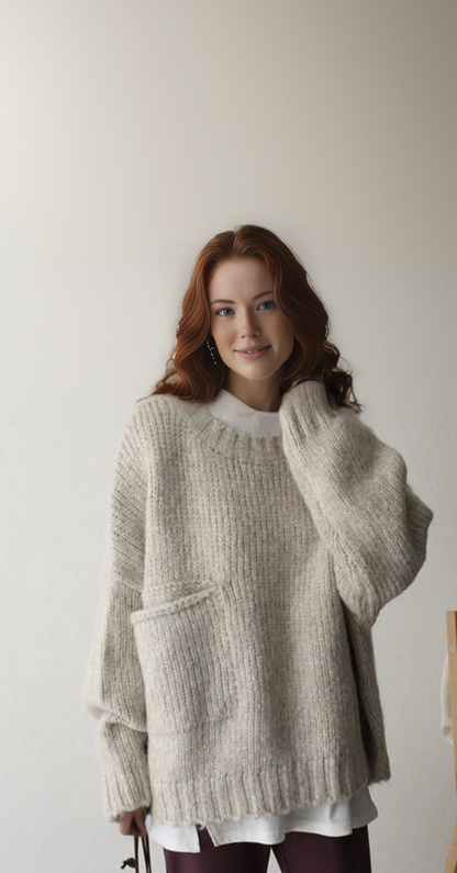 Eine Frau trägt einen beigen Strickpullover mit Tasche, lässiger Herbstmode.