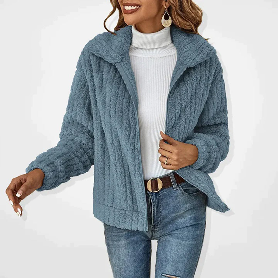Frau in blauer Plüschjacke, weißem Rollkragenpullover, Jeans; modische Winterbekleidung.