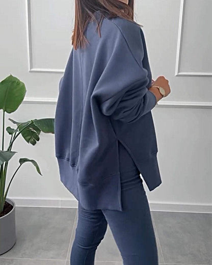 Frau in dunkelblauem Oversize-Sweatshirt und Leggings, moderne Freizeitmode, Zimmerpflanze.