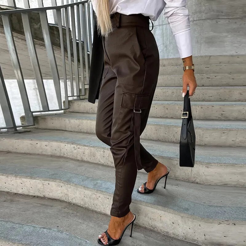 Frau in brauner Lederhose, weißer Bluse, schwarzen High Heels, schwarze Handtasche, Treppe.