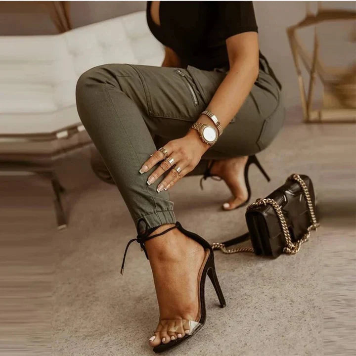 Frau in olivgrüner Cargo-Jeans, schwarze High Heels, schwarze Handtasche, modisch, elegant.
