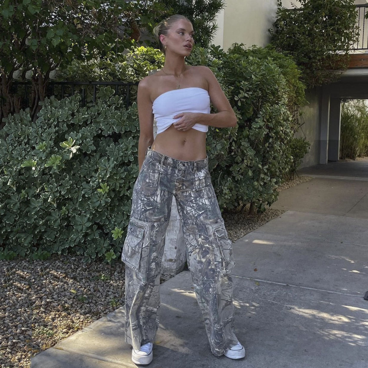 Frau in weißem Bandeau-Top und grauer Cargohose, lässiger Sommerlook, draußen.
