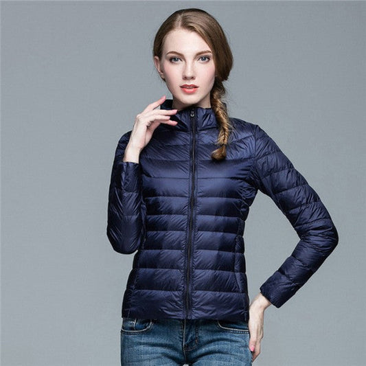 Frau in dunkelblauer Daunenjacke, Stehkragen, Reißverschluss, modisch, warm, Winterbekleidung.