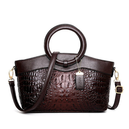 Damenhandtasche aus braunem Leder mit Krokodilprägung, runder Griff, verstellbarer Schulterriemen.
