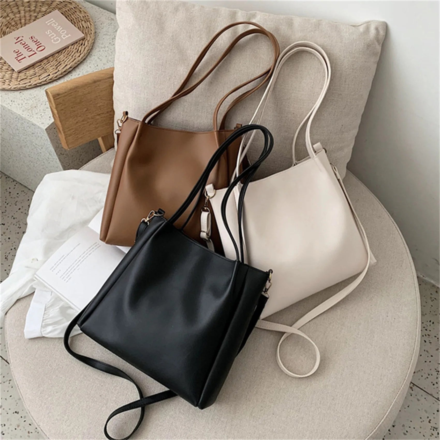 Drei Ledertaschen in Schwarz, Braun und Weiß auf einem Sofa, modisch, elegant, Damenhandtaschen.