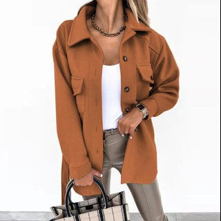 Frau in brauner Jacke, weißem Top, beiger Hose, hält karierte Tasche, modisch, elegant.