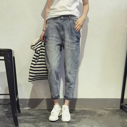 Frau in blauer Jeans und weißen Sneakers, hält gestreifte Tasche, lässiger Look.