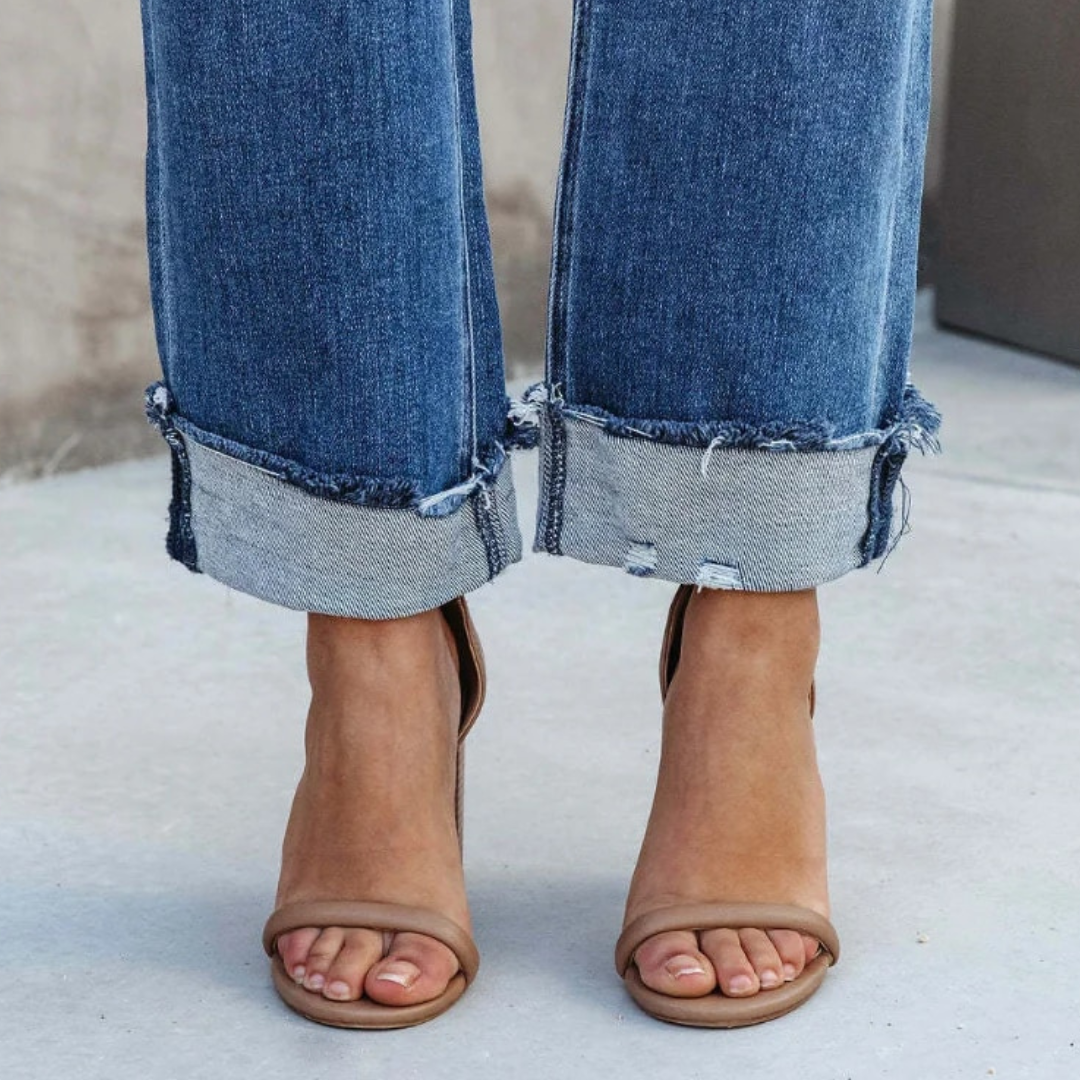 Damenjeans mit ausgefranstem Saum, blaue Denim, modische Sandalen, lässiger Stil.