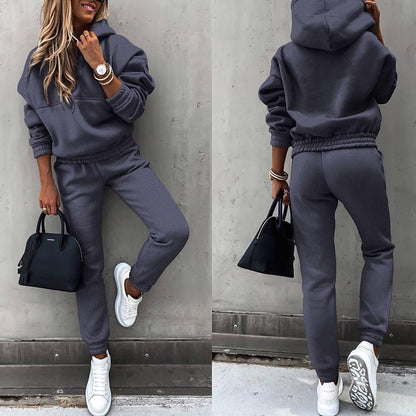Frau in grauem Jogginganzug, weiße Sneaker, schwarze Handtasche, lässiger Look, Streetwear.
