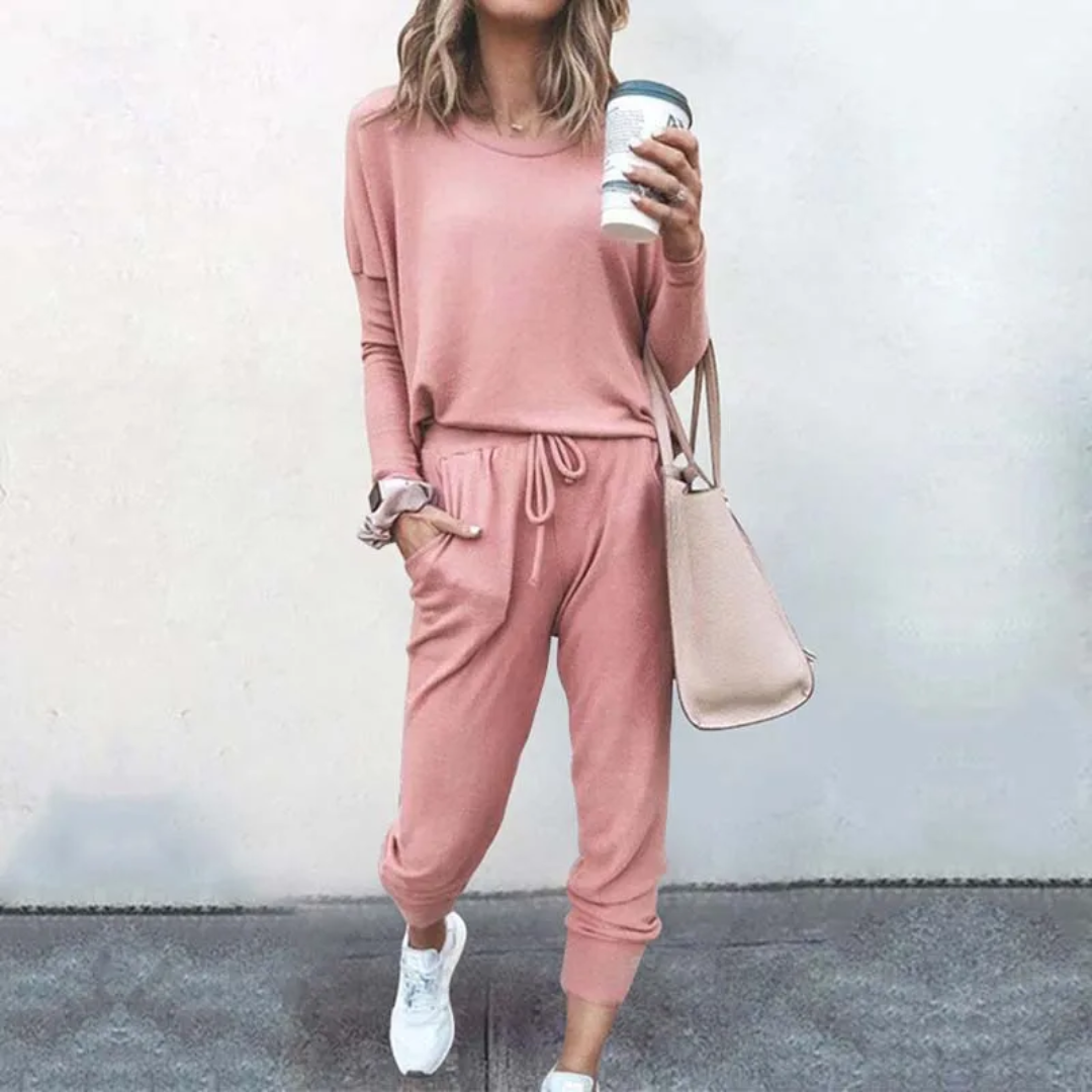 Frau in rosa Freizeitanzug mit Kaffeebecher und Tasche, lässige Mode, bequeme Damenbekleidung.
