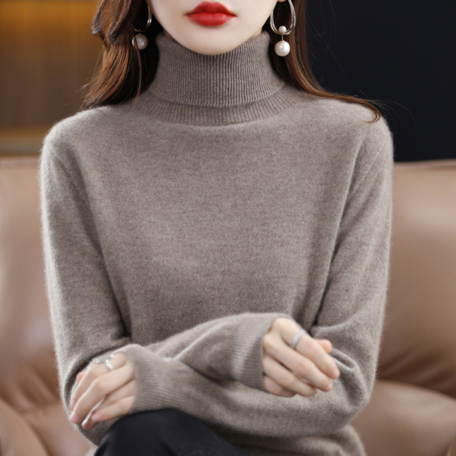 Frau in grauem Rollkragenpullover aus Kaschmir, elegante Perlenohrringe, modisch, stilvoll.