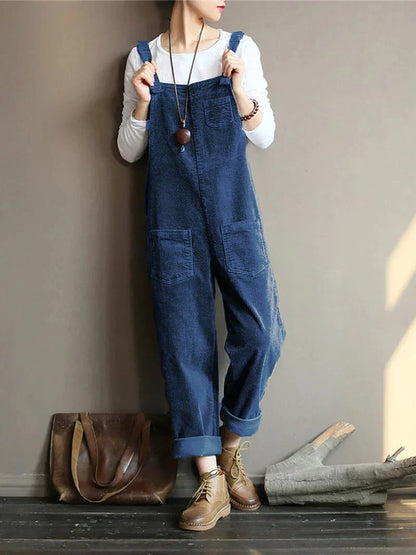 Frau in blauer Latzhose aus Denim, weißem Langarmshirt, braunen Stiefeln, brauner Ledertasche.