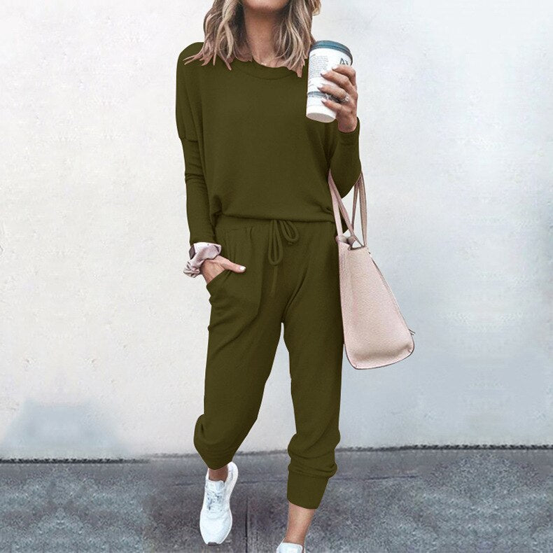 Frau in olivgrünem Freizeitanzug mit Kaffeebecher und beiger Tasche, lässige Mode.