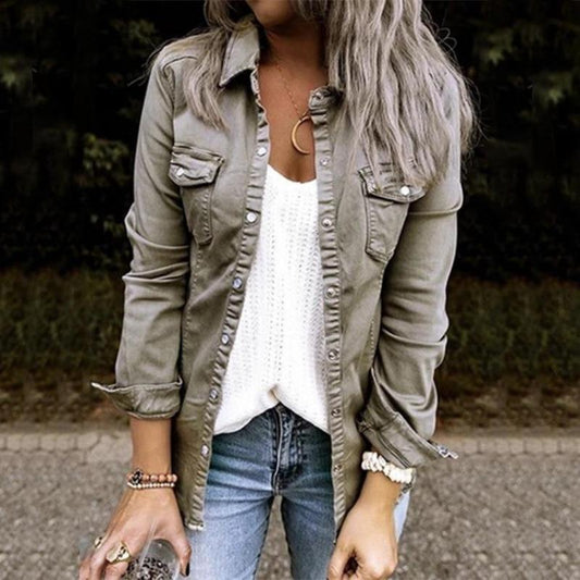Frau in olivgrüner Jeansjacke, weißem Top und blauer Jeans im Freien.