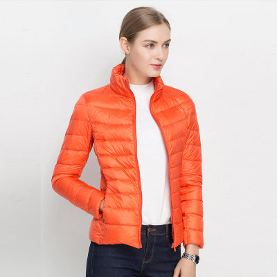 Frau in orangefarbener Daunenjacke, Stehkragen, weißes Shirt, blaue Jeans, modisch, Herbstmode.