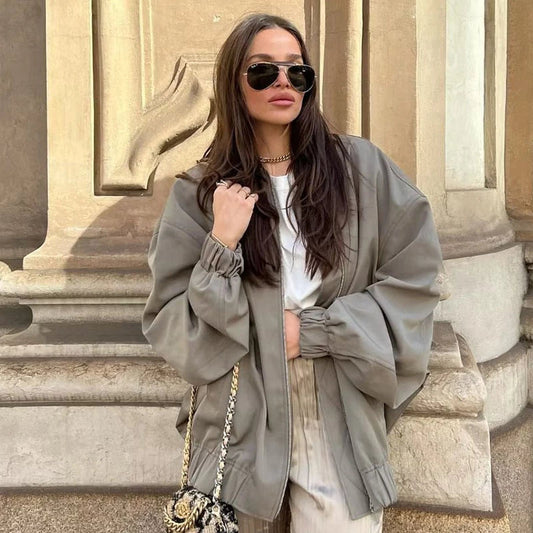 Frau in übergroßer, grauer Herbstjacke, Sonnenbrille, modische Handtasche, lässiger Stil.