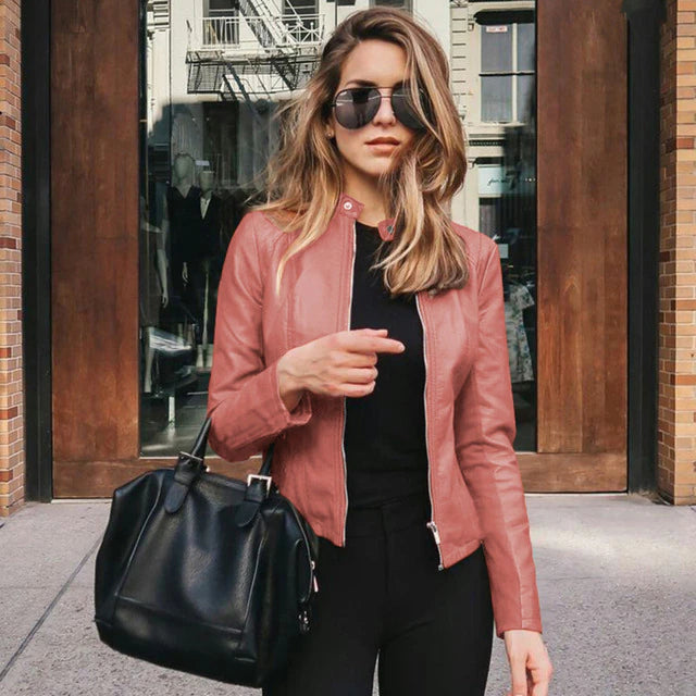 Frau in roter PU-Lederjacke, schwarze Tasche, Sonnenbrille, urbaner Hintergrund.