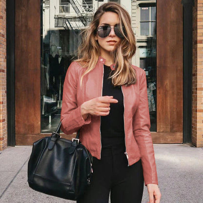 Frau in roter PU-Lederjacke, schwarze Tasche, Sonnenbrille, urbaner Hintergrund.