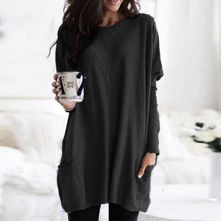 Frau in langem, schwarzem Pulloverkleid mit Kaffeetasse, gemütliche Wintermode.