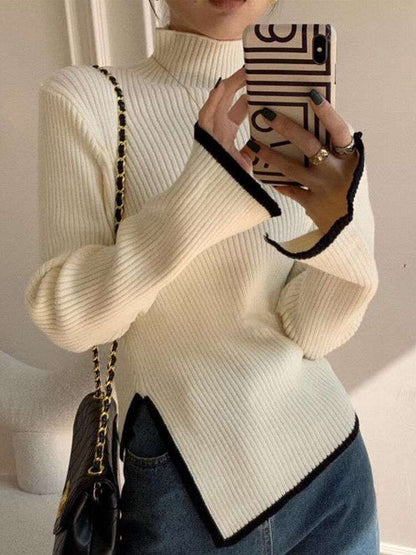 Frau in cremefarbenem Strickpullover mit schwarzem Rand, Smartphone, Jeans, modisch.