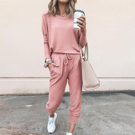 Frau in rosa Freizeitanzug mit Kaffeebecher und beiger Tasche, lässige Mode.