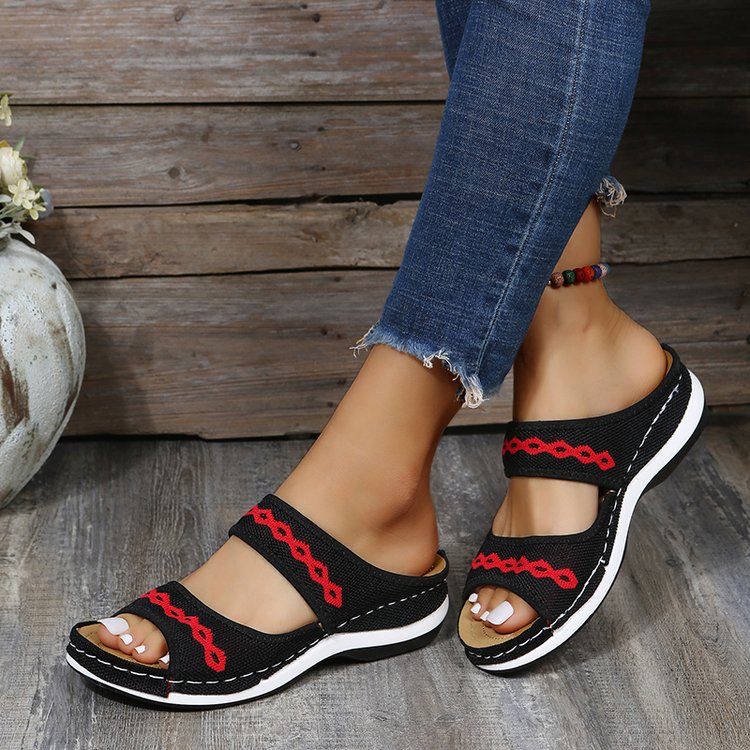Schwarze Damen-Sandalen mit rotem Muster, bequem, lässig, ideal für Sommer, Jeans-Hintergrund.