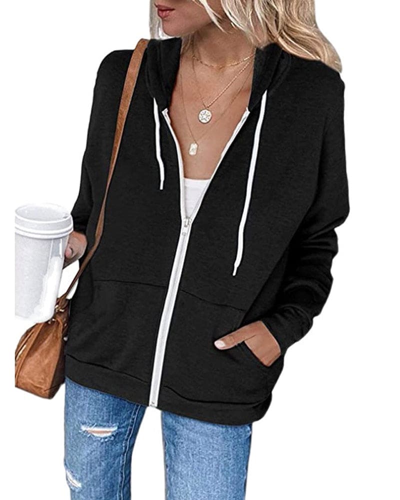 Frau in schwarzem Kapuzenpullover mit Reißverschluss, weiße Kordeln, blaue Jeans, Kaffeebecher.