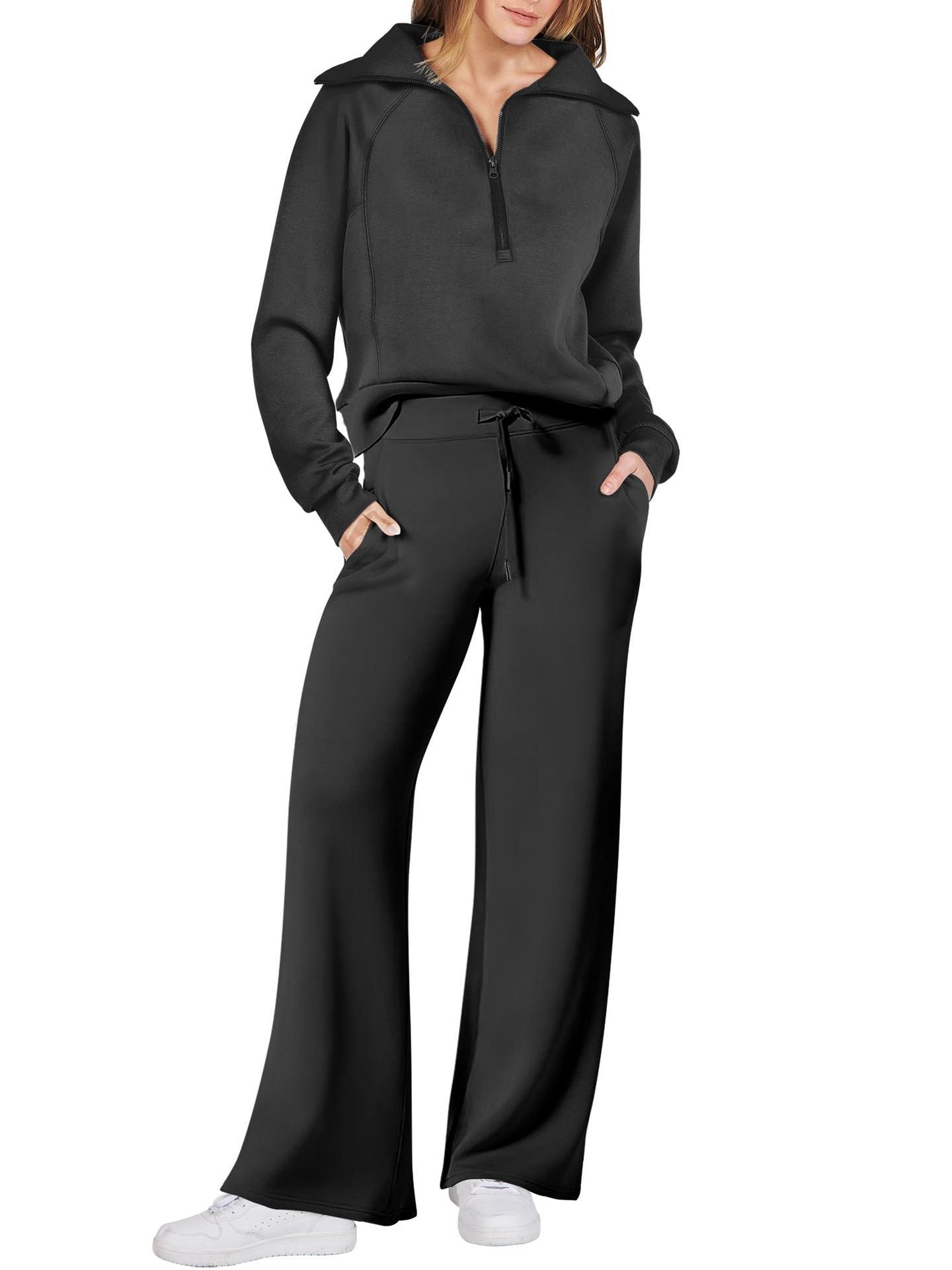 Frau in schwarzem Freizeitanzug mit weitem Schnitt und weißen Sneakers, modisch und bequem.