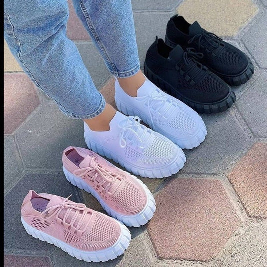Drei Paar Sneaker in Rosa, Weiß und Schwarz auf Pflastersteinen, Damenmode, Freizeitschuhe.