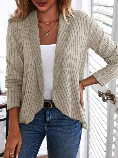 Frau trägt beige Strickjacke, weißes Top, blaue Jeans, modisch, lässig, Damenmode.