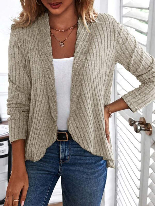 Frau trägt beige Strickjacke, weißes Top, blaue Jeans, modisch, lässig, Damenmode.