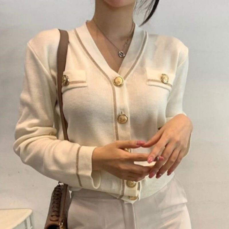 Frau trägt cremeweißen Cardigan mit goldenen Knöpfen, elegantes Design, modische Damenbekleidung.