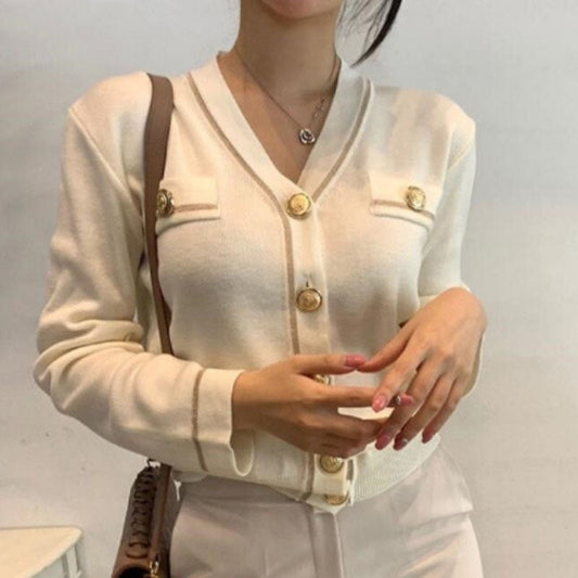 Frau trägt cremeweißen Cardigan mit goldenen Knöpfen, elegantes Design, modische Damenbekleidung.