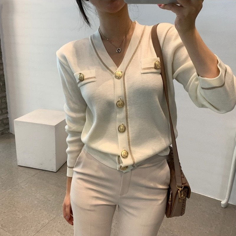 Frau in cremefarbenem Strickcardigan mit goldenen Knöpfen, elegantes Outfit, modisch.