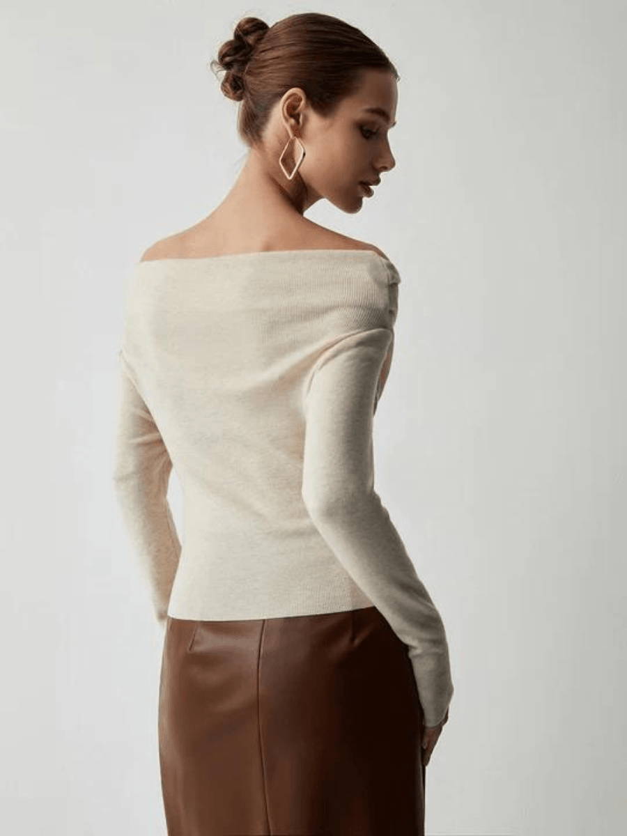 Frau in cremefarbenem Off-Shoulder-Pullover und braunem Lederrock, elegantes Outfit.