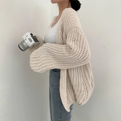 Frau in cremefarbenem Strickweste, hält Kamera, modisch, bequem, Damenmode.