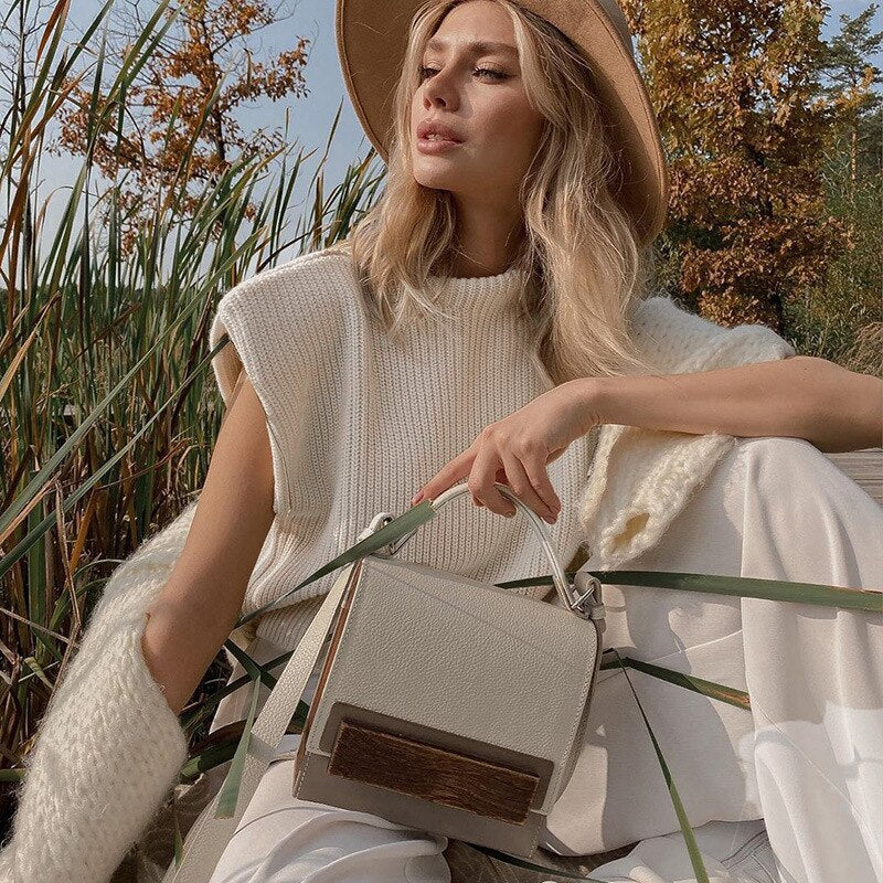 Frau mit beiger Strickweste, Hut und weißer Handtasche im Herbst, Mode, Outdoor, stilvoll.