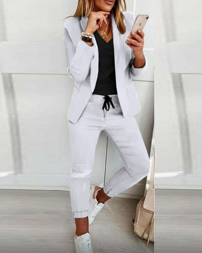 Frau im weißen Anzug mit Smartphone, schwarze Bluse, lässiger Look, moderne Damenmode.