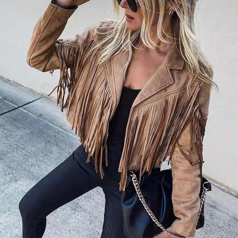 Frau in brauner Wildlederjacke mit Fransen, schwarze Hose, Sonnenbrille, schwarze Tasche.