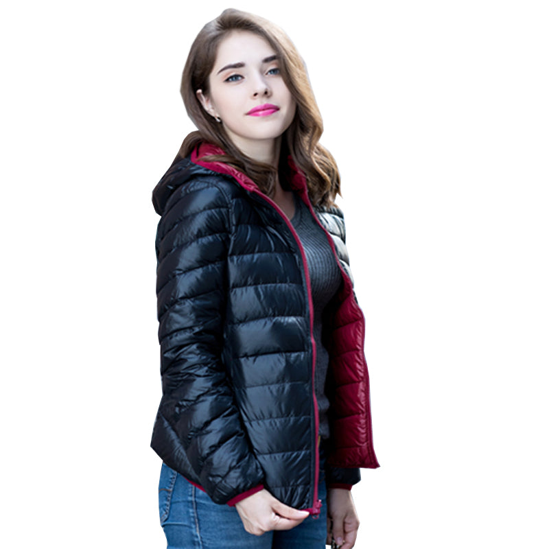 Frau in schwarzer Daunenjacke mit Kapuze, rote Innenseite, Wintermode, Outdoor-Bekleidung.