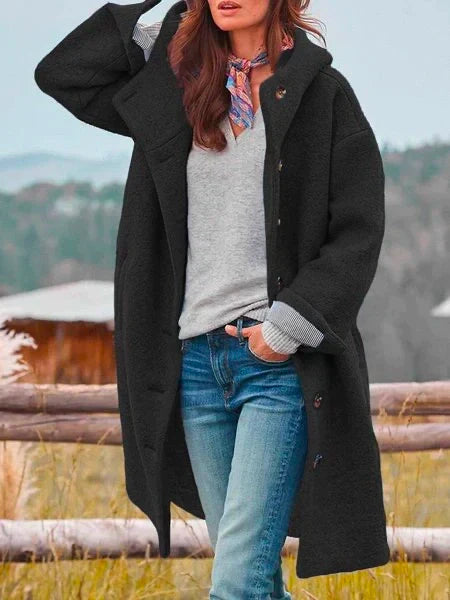Frau in schwarzem Wollmantel, grauem Pullover, Jeans, bunter Schal, Herbstlandschaft.