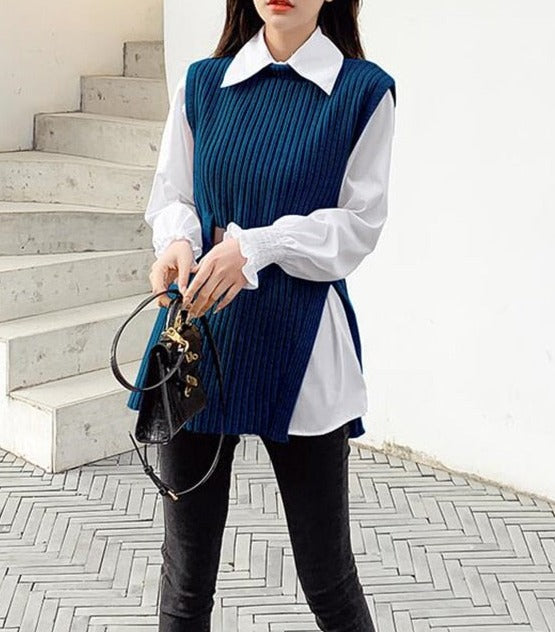 Frau in blauem Strickpullover mit weißer Bluse, schwarze Hose, modisches Outfit, Handtasche.