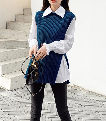 Frau in blauem Strickpullover mit weißer Bluse, schwarze Hose, modisches Outfit, Handtasche.