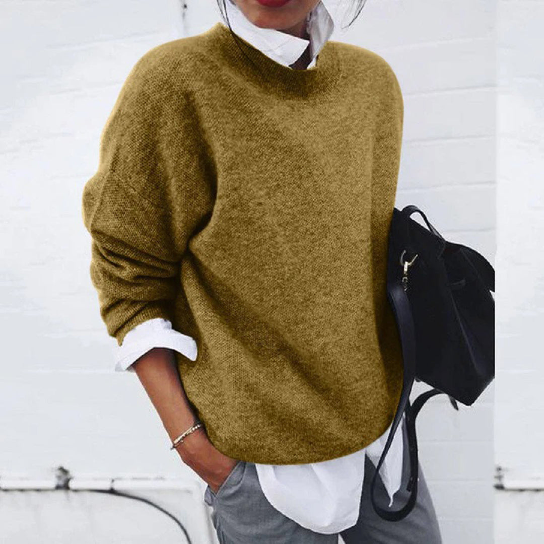 Damenpullover aus Wolle, beige, lässig, Herbstmode, kombiniert mit weißer Bluse und schwarzer Tasche.